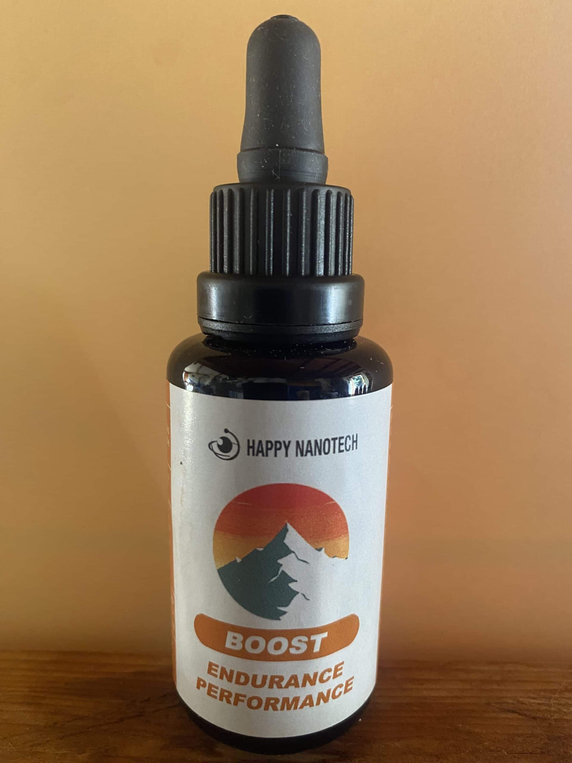 Flacon compte-gouttes Happy Nanotech BOOST pour endurance et performance. Étiquette blanche avec montagne stylisée et coucher de soleil.