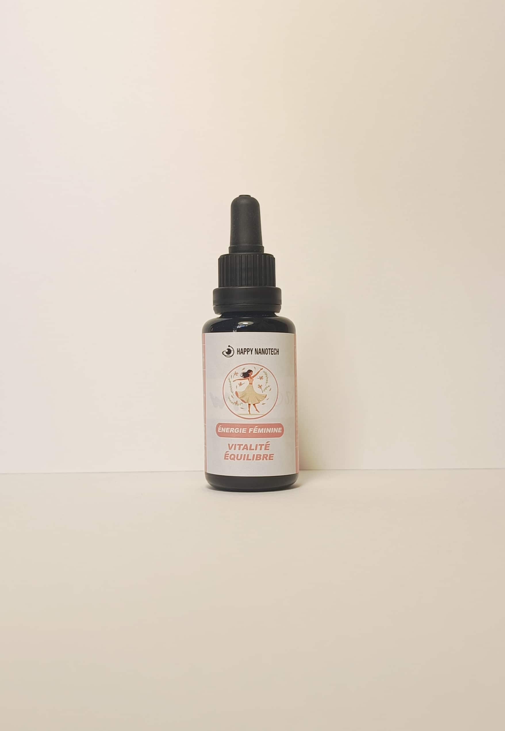 Flacon compte-gouttes noir HAPPY NANOTECH. Étiquette rose/blanc : danseuse, texte ÉNERGIE FÉMININE VITALITÉ ÉQUILIBRE.